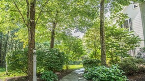 A pathway leading to a house surrounded by lush greenery and trees. - Large Luxury Family Home Near Five Colleges. The TOP short term rental in area! (Hadley)