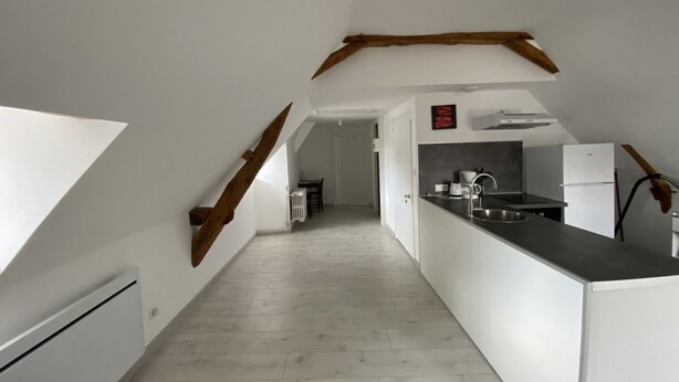 A modern kitchen with white cabinetry, a black countertop, and a wooden beam ceiling. - Cozy 1-Bedroom Apartment Near Saint Roch Thermal Baths, La Roche-Posay (La Roche-Posay)