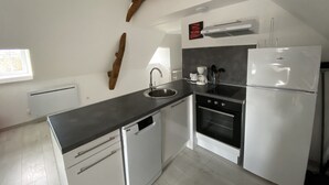 A modern kitchen with white cabinetry, a black countertop, and a built-in oven. - Cozy 1-Bedroom Apartment Near Saint Roch Thermal Baths, La Roche-Posay (La Roche-Posay)