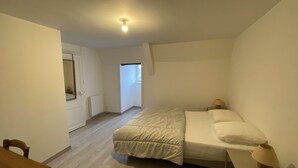 A bedroom with a bed, bedside table, lamp, and a view of a hallway. - Cozy 1-Bedroom Apartment Near Saint Roch Thermal Baths, La Roche-Posay (La Roche-Posay)
