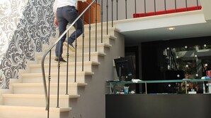 A man ascending a staircase with a patterned wall and a flat-screen TV mounted on the wall. - Hotel De Notelaer (Bornem)