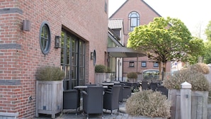 A brick building with outdoor seating and a covered patio area. - Hotel De Notelaer (Bornem)