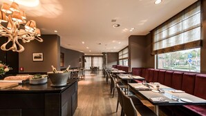 A modern restaurant interior with wooden flooring, dark-toned booths, and a central bar area with bottles. - Hotel De Notelaer (Bornem)
