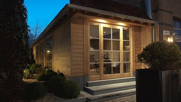 A wooden building with large glass doors, a brick exterior, and a paved entrance area. - Hotel De Notelaer (Bornem)