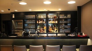 A bar area with a counter, shelves of bottles and glasses, and seating. - Hotel De Notelaer (Bornem)