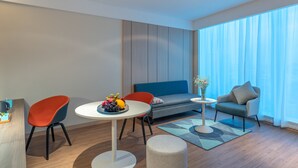 Uma sala de estar moderna com uma mesa redonda, duas cadeiras, um sofá e uma pequena mesinha de canto com um vaso.