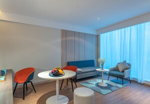 A modern living room with a round table, two chairs, a sofa, and a small side table with a vase. - Holiday Inn Express Changsha Wuyi Plaza by IHG (Changsha)