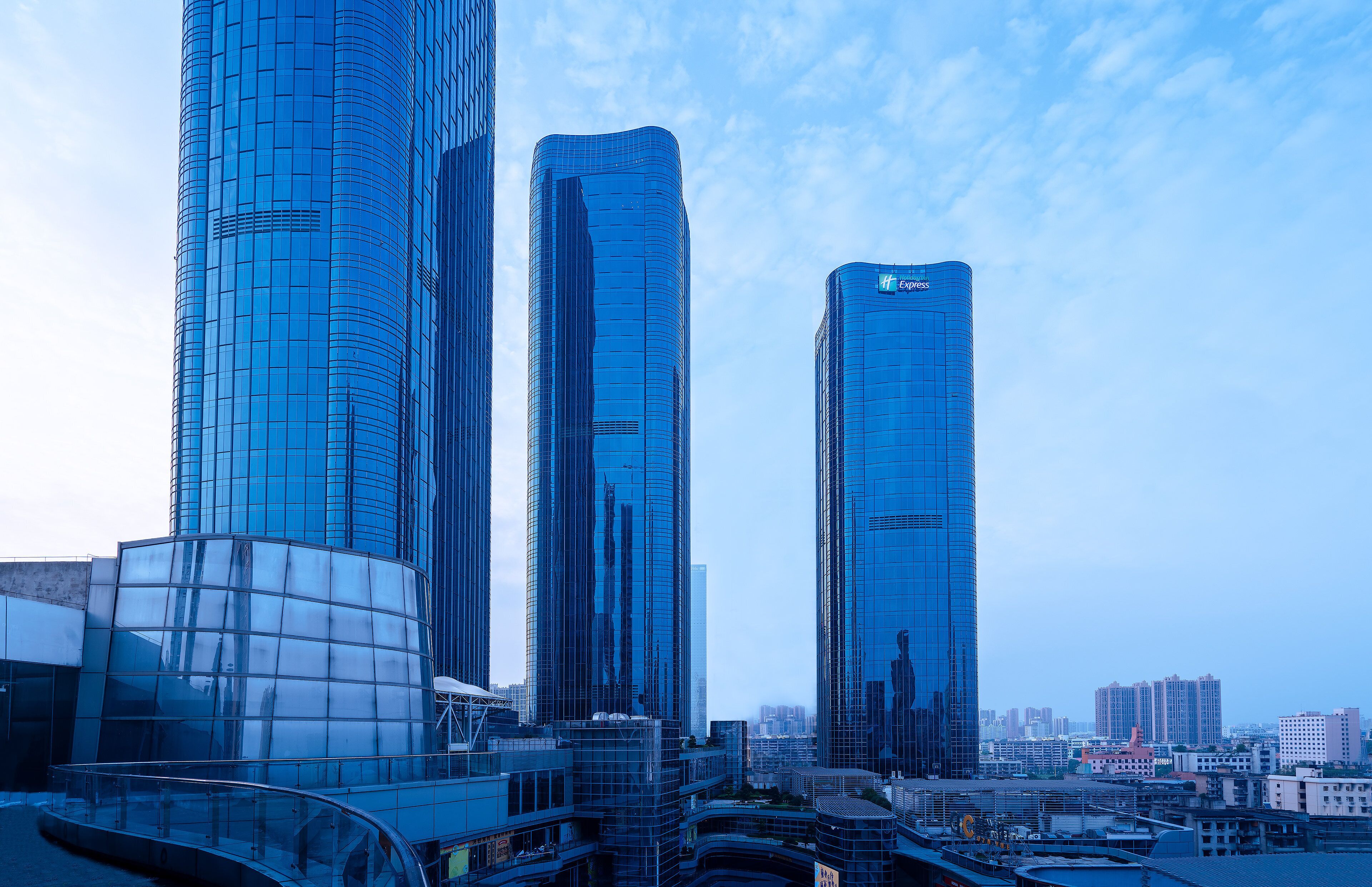 A modern high-rise building with a curved glass facade, multiple floors, and a prominent 'Holiday Inn Express' sign.