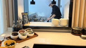 A modern kitchen with a chef preparing food, a menu board, and various cooking utensils and ingredients. - Holiday Inn Express Changsha Wuyi Plaza by IHG (Changsha)