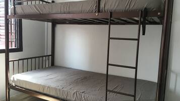 Una cama litera con escalera, una ventana con barrotes y una pared lisa.