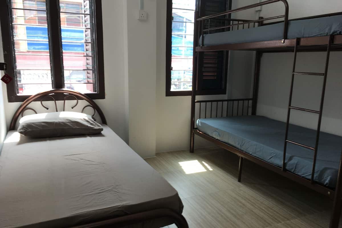 A dormitory room with a single bed, a bunk bed, and a window with blinds.