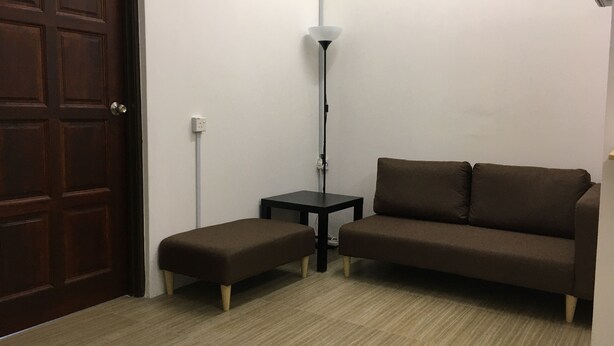 A room with a brown door, a brown sofa, a small black table, and a floor lamp. - Homey Hostel, Ipoh Town (Ipoh)