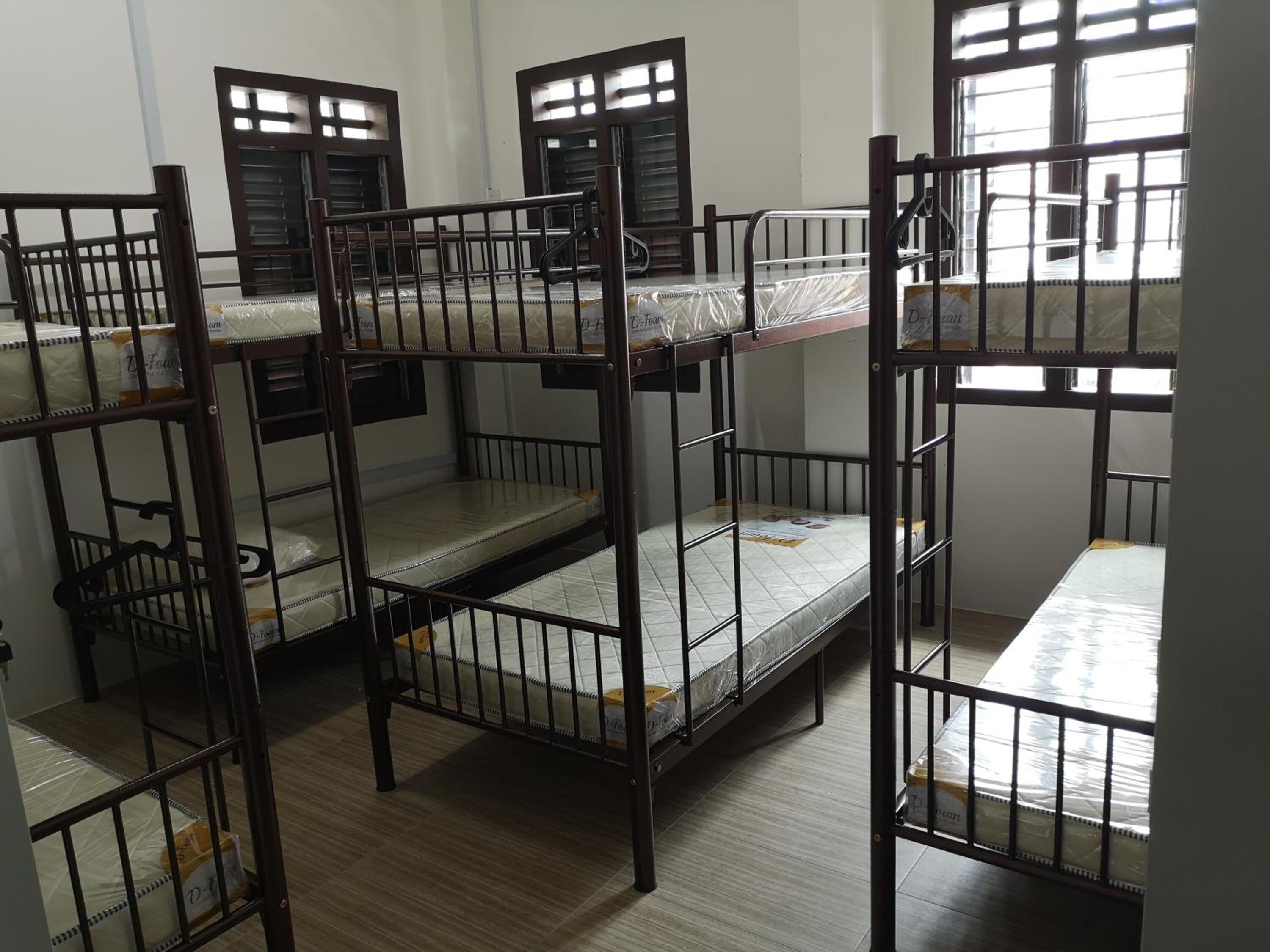 Camas literas en una habitación con piso de madera y ventanas con persianas.