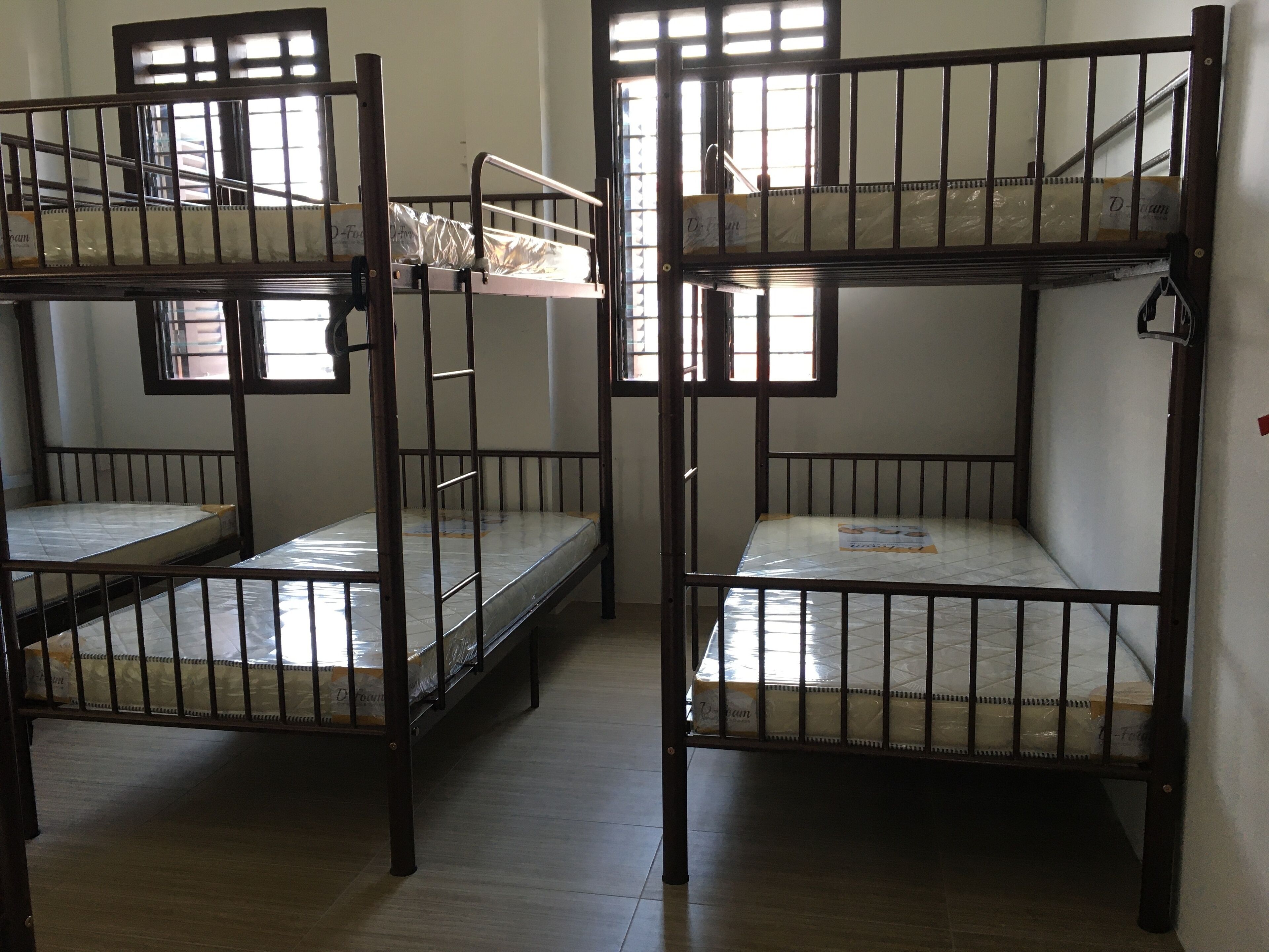 Bunk beds in a dormitory room with wooden railings and a tiled floor.