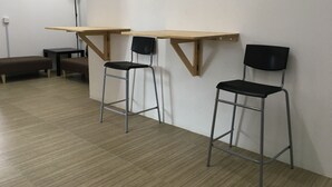 A room with a wooden desk, two black chairs, a bench, and a floor lamp. - Homey Hostel, Ipoh Town (Ipoh)