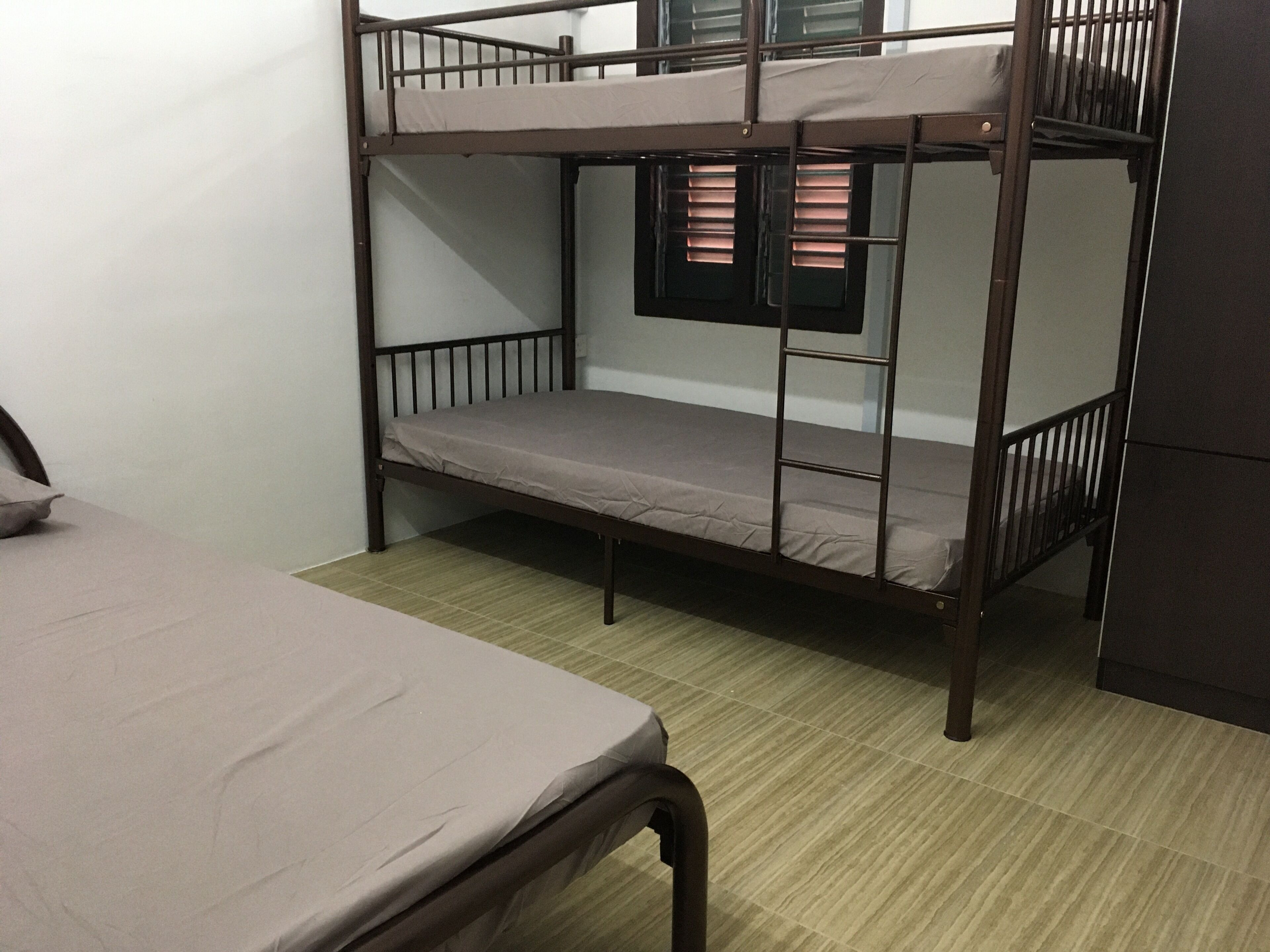 Habitación con literas, una cama individual en la parte inferior y una ventana con persianas.