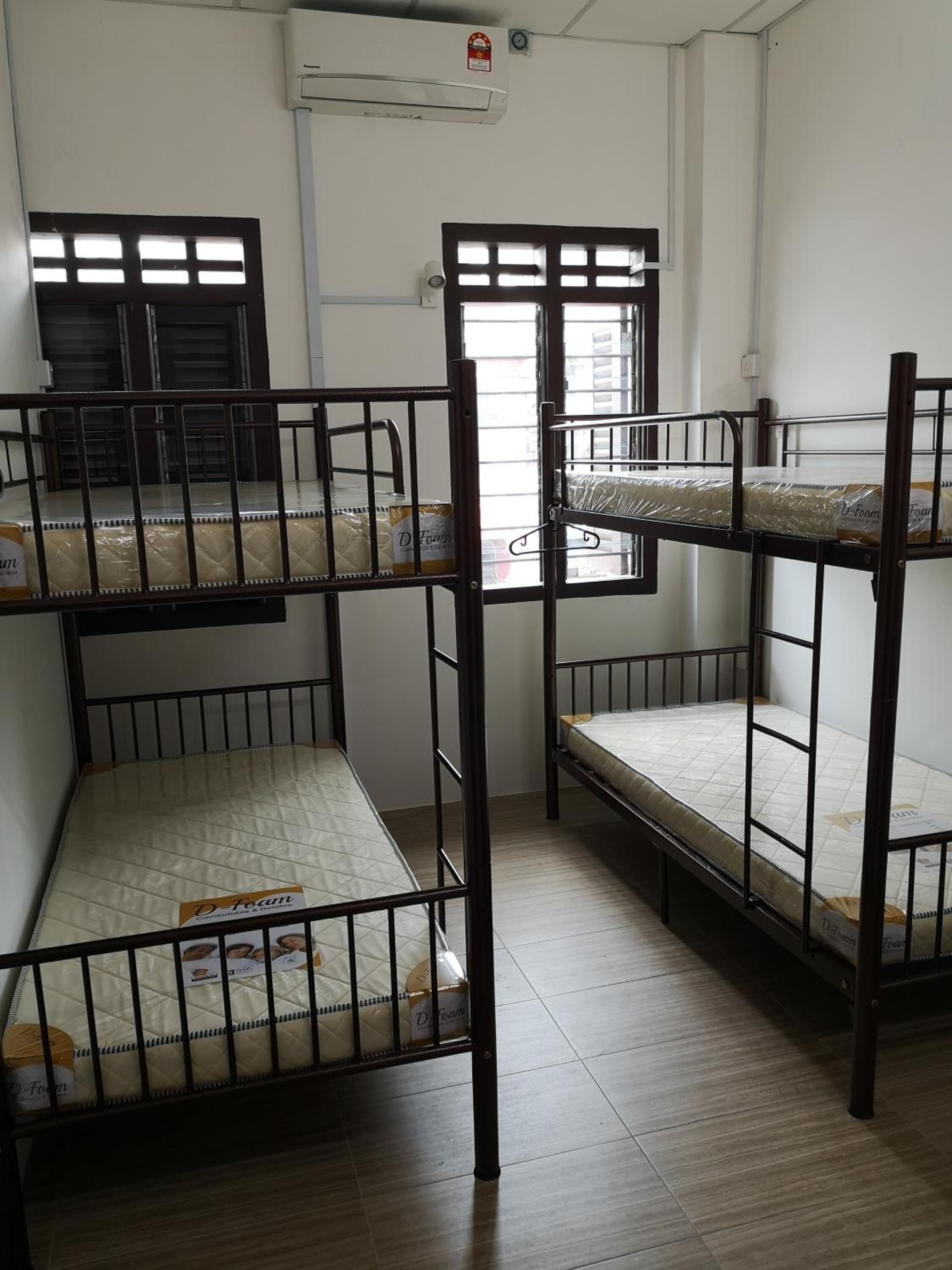 A room with bunk beds, an air conditioning unit, and a window with blinds.