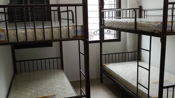 A room with bunk beds, an air conditioning unit, and a window with blinds.