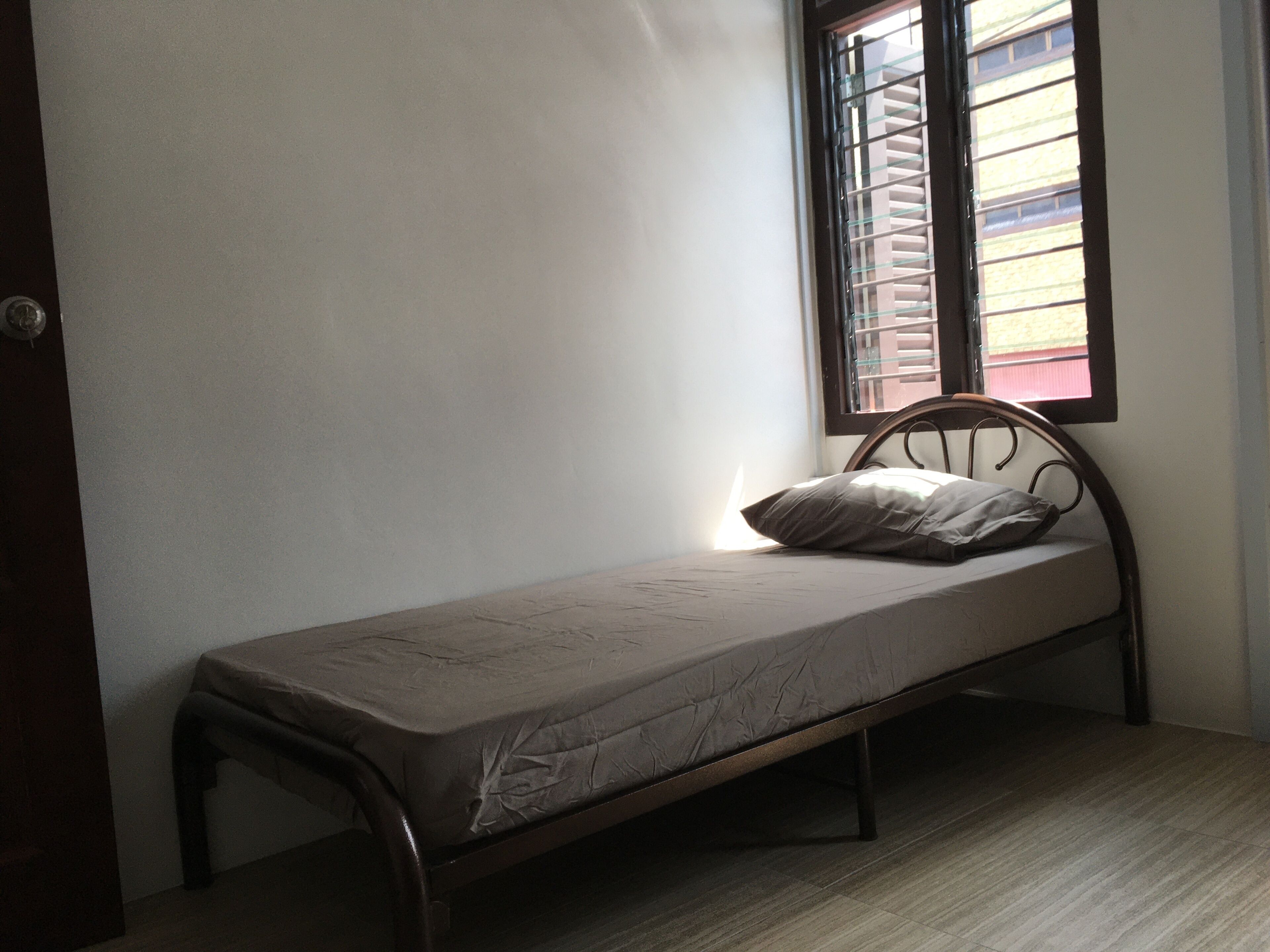 Une petite chambre avec un lit simple, un cadre en bois, un matelas et un oreiller.