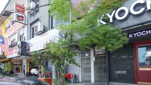 Vista de la calle con un restaurante llamado 'Restoran' y una tienda llamada 'KYOCHE'.