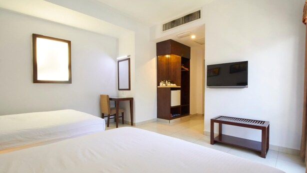 A hotel room with two beds, a desk, a chair, a wardrobe, a TV, and a bench. - Kepong Hotel (Kuala Lumpur)