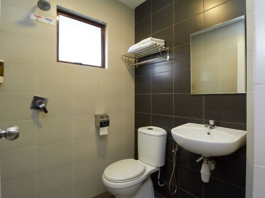 Une salle de bain équipée de toilettes, d’un lavabo, d’un porte-serviettes et d’une fenêtre.