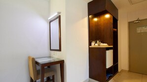 A hotel room with a wooden desk, a mirror, a built-in wooden cabinet with a sink, and a door with a notice. - Kepong Hotel (Kuala Lumpur)