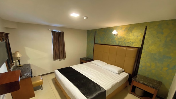 A hotel room with a bed, bedside table, lamp, and a small wooden nightstand. - Hotel Bliss Johor Bahru Skudai (Johor Bahru)