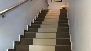 A staircase with alternating dark and light steps, a handrail on the left, and a small table with a lamp at the top. - Hotel Bliss Johor Bahru Skudai (Johor Bahru)