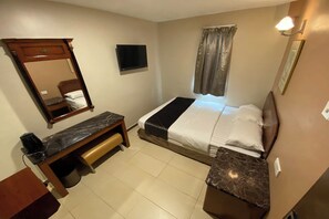 A hotel room with a bed, a desk, a mirror, a TV, and a window with curtains. - Hotel Bliss Johor Bahru Skudai (Johor Bahru)
