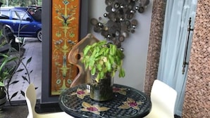 A small outdoor seating area with two white chairs and a round table, a potted plant, and a decorative wall piece. - Hotel Bliss Johor Bahru Skudai (Johor Bahru)
