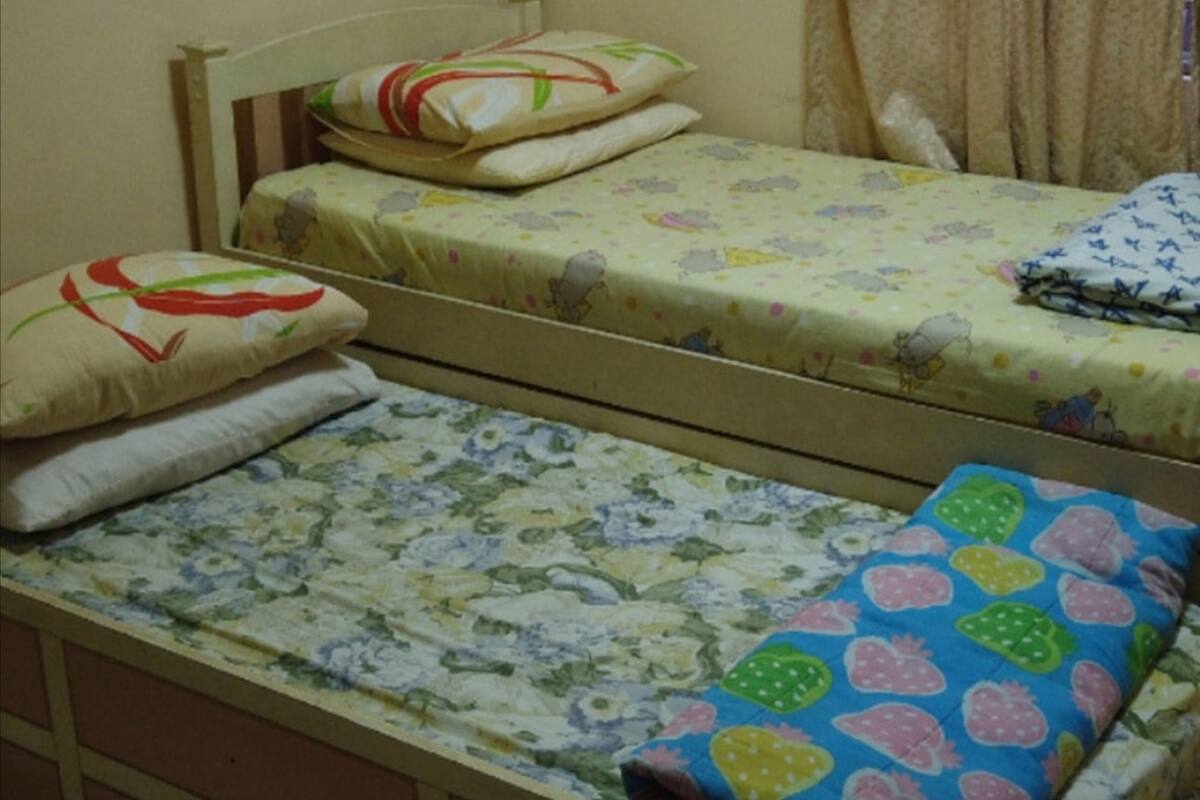 A single-bed room with a wooden headboard, floral bedding, and a small bedside table.
