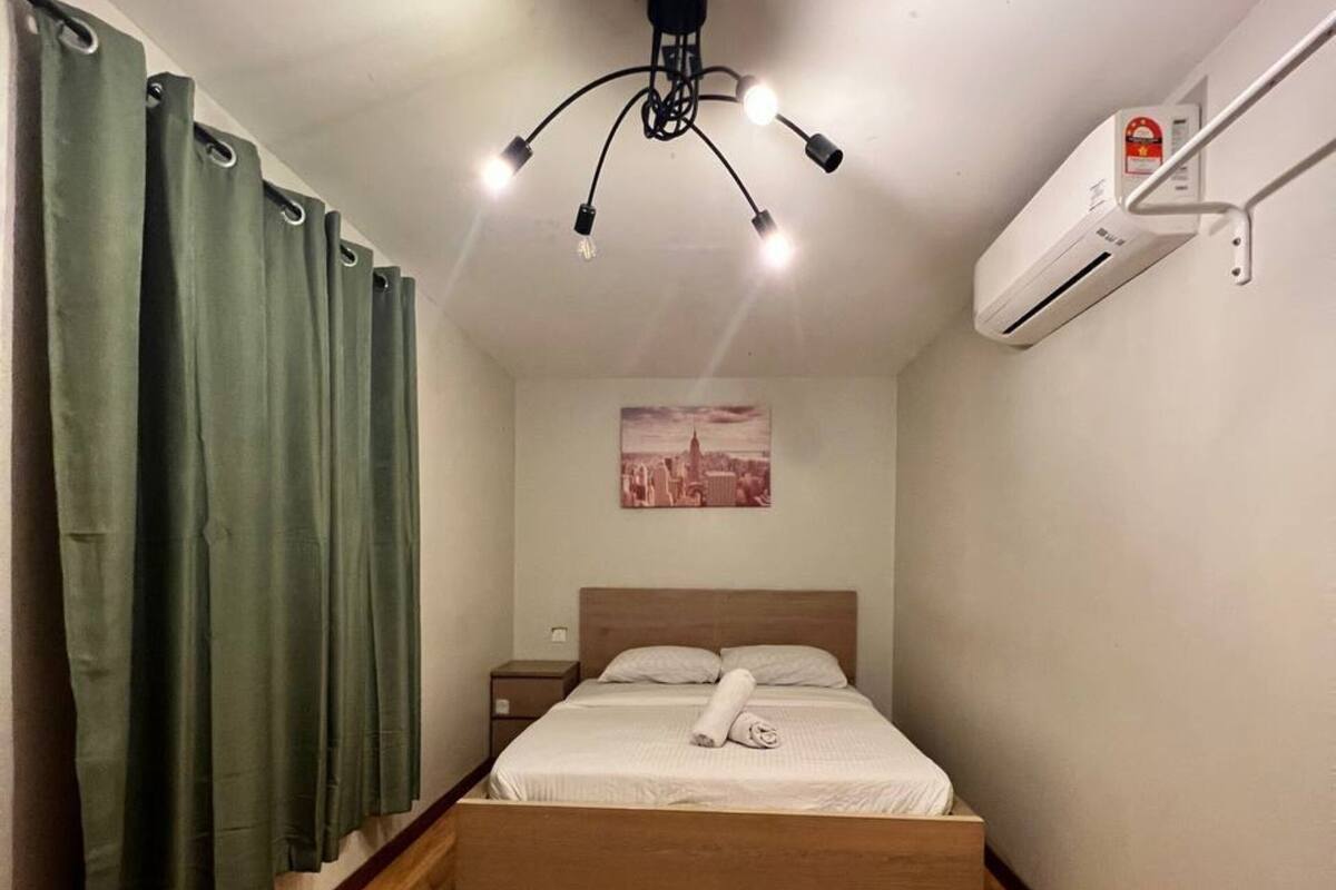 Ein kleines, ordentlich eingerichtetes Schlafzimmer mit einem Einzelbett, einem Nachttisch, einer Wand-Klimaanlage und einem Stadtbild an der Wand.