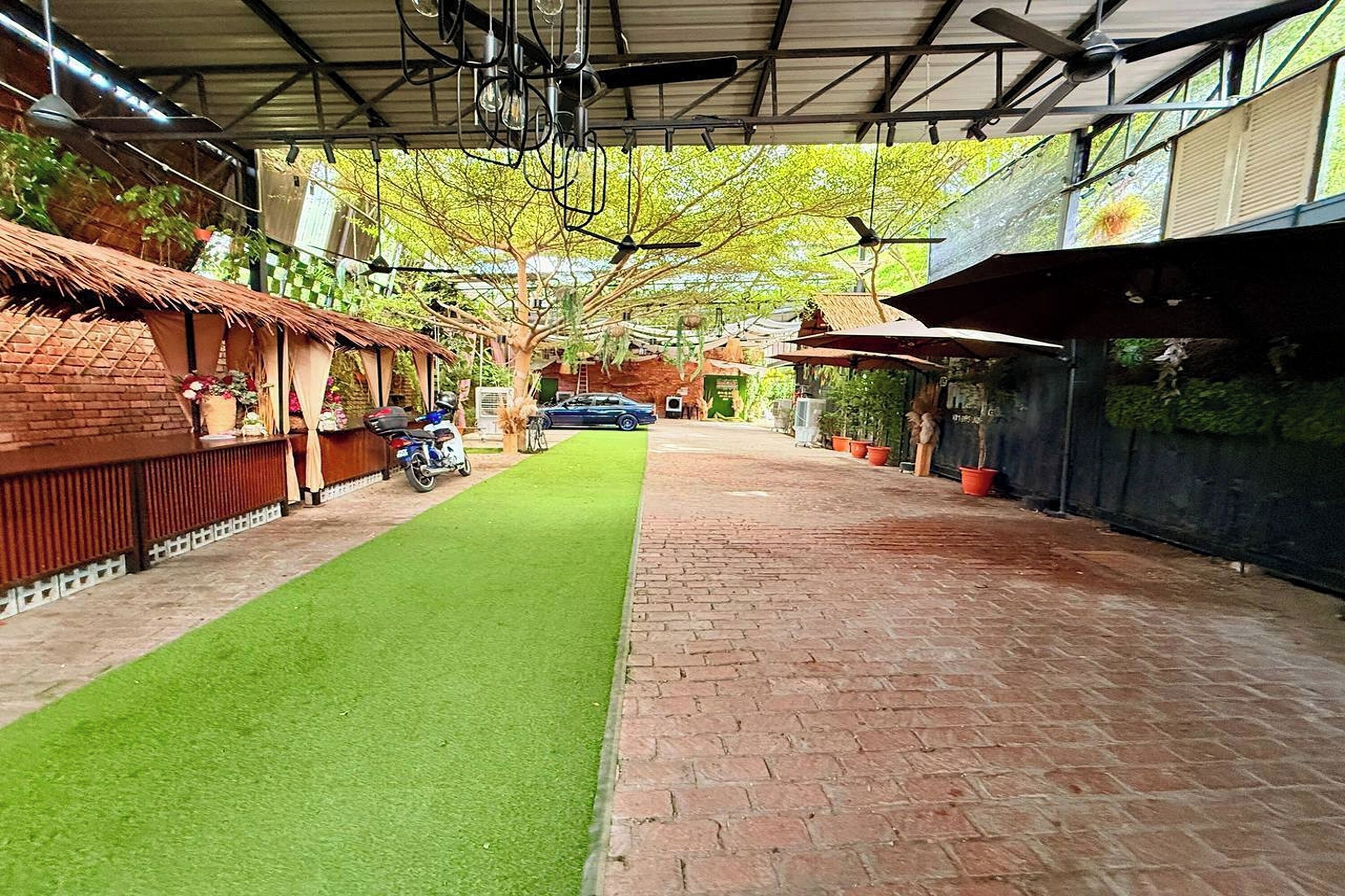 A covered outdoor area with a paved walkway, a green artificial turf, and a parked car.