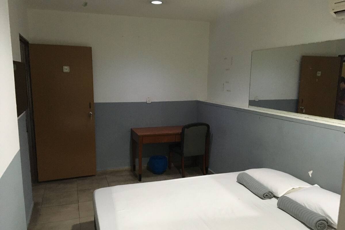 Ein Hotelzimmer mit Bett, Schreibtisch, Stuhl und Kleiderschrank.