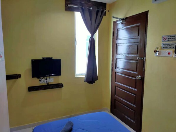 A room with a bed, a television mounted on the wall, a window with curtains, and a door with a sign indicating no smoking. - CSH Motel Kuala Perlis (Kuala Perlis)