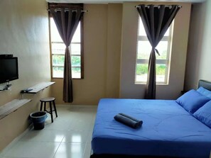 A bedroom with a bed, a TV, a small stool, and a window with curtains. - CSH Motel Kuala Perlis (Kuala Perlis)