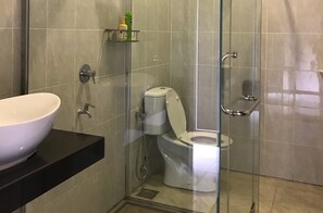 A modern bathroom with a glass-enclosed shower, a white toilet, and a black countertop with a white vessel sink. - Singgahsana Villa by Zuzu (Langkawi)