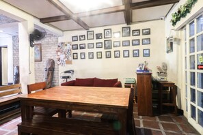 Una habitación acogedora con una mesa de madera y bancos, un sofá rojo y una pared decorada con cuadros.