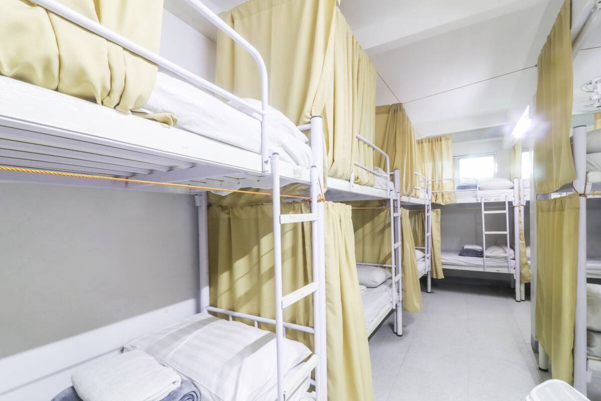 Una habitación tipo dormitorio con literas, cortinas amarillas y una ventana.