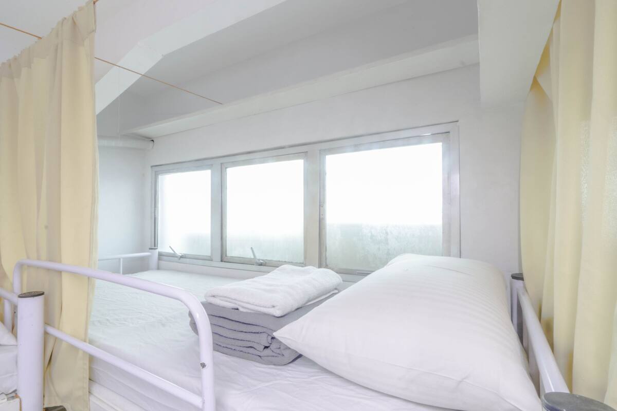 Una habitación de hospital con cama, ventana y cortina.