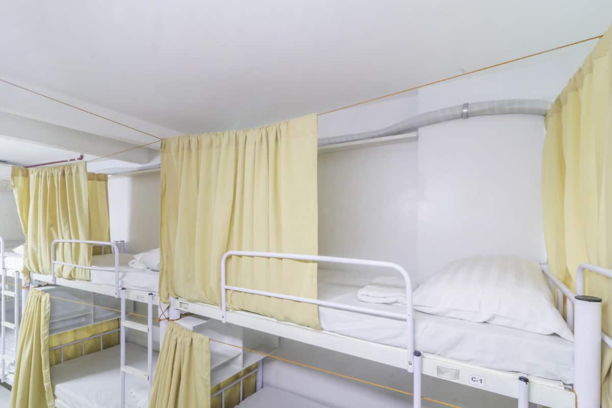 Una sala de hospital con literas, cada una con una cortina y un almohadón blanco.
