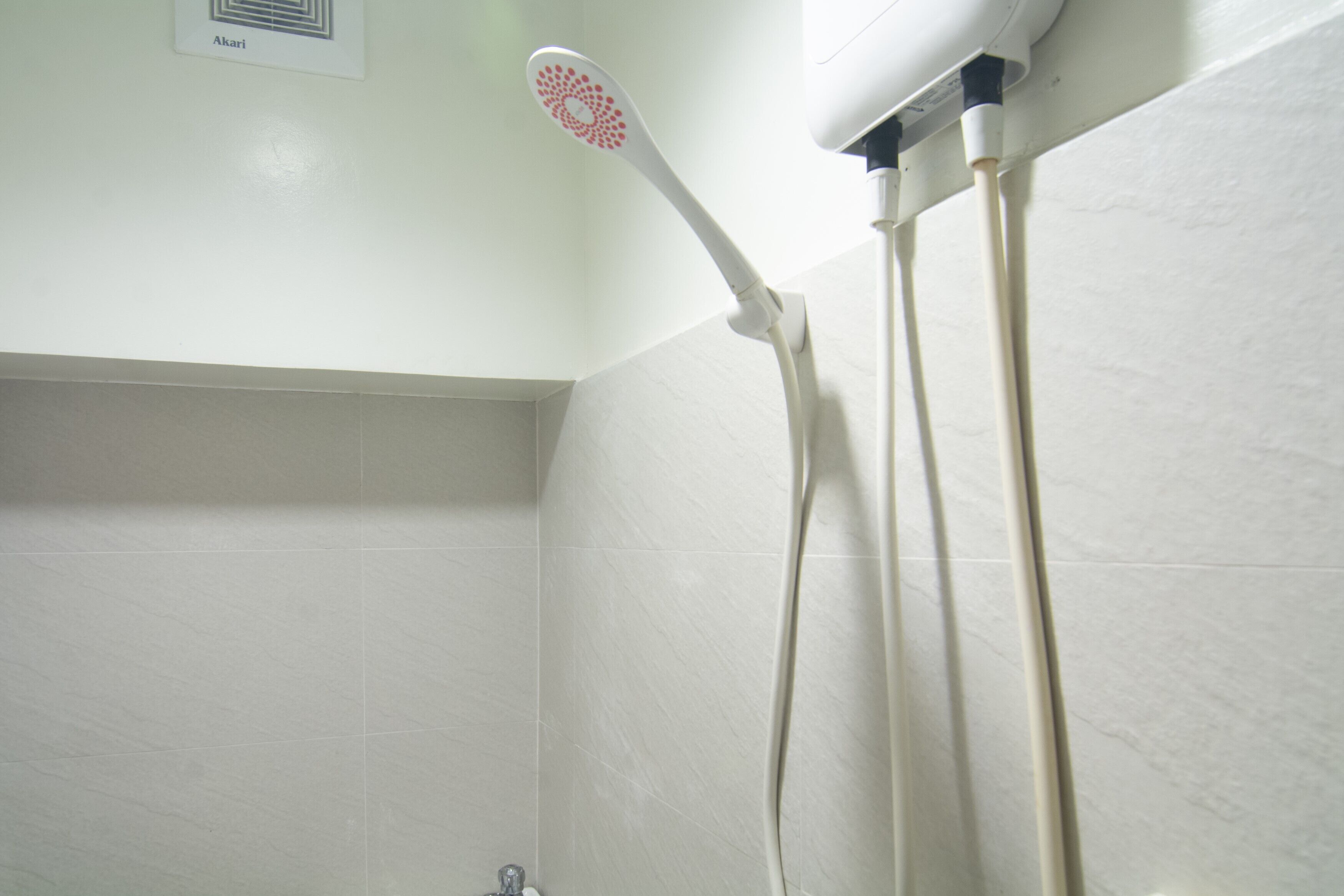 A shower with a handheld showerhead and a wall-mounted control panel.