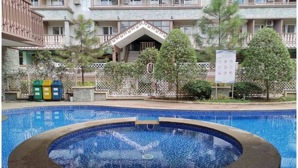A hotel with a swimming pool, a covered area, and a fenced garden. - SweetSuites at Pine Crest New Manila (Quezon City)