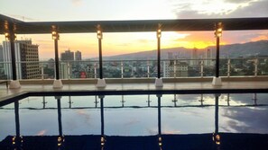 Ein Dachpool mit Blick auf die Stadt bei Sonnenuntergang, umgeben von modernen Gebäuden und einem klaren Himmel.