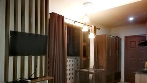 A living room with a flat-screen TV, a glass-top table, and a wooden cabinet.