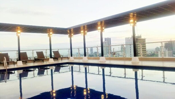 A rooftop infinity pool with lounge chairs and city views.