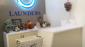 A reception area with a 'LAUNDERS' sign, a vase with dried flowers, a framed picture, and a small plant.