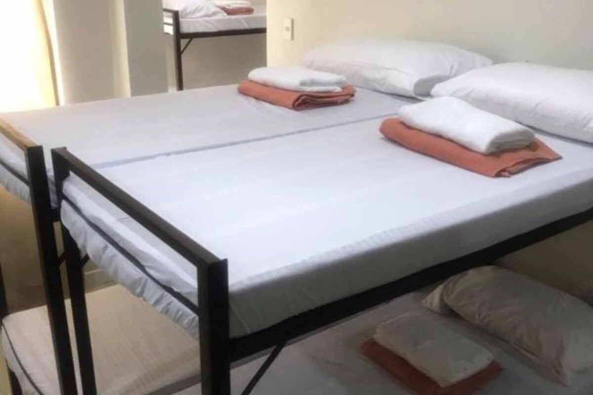 A single bed with a black frame, white bedding, and neatly folded towels.