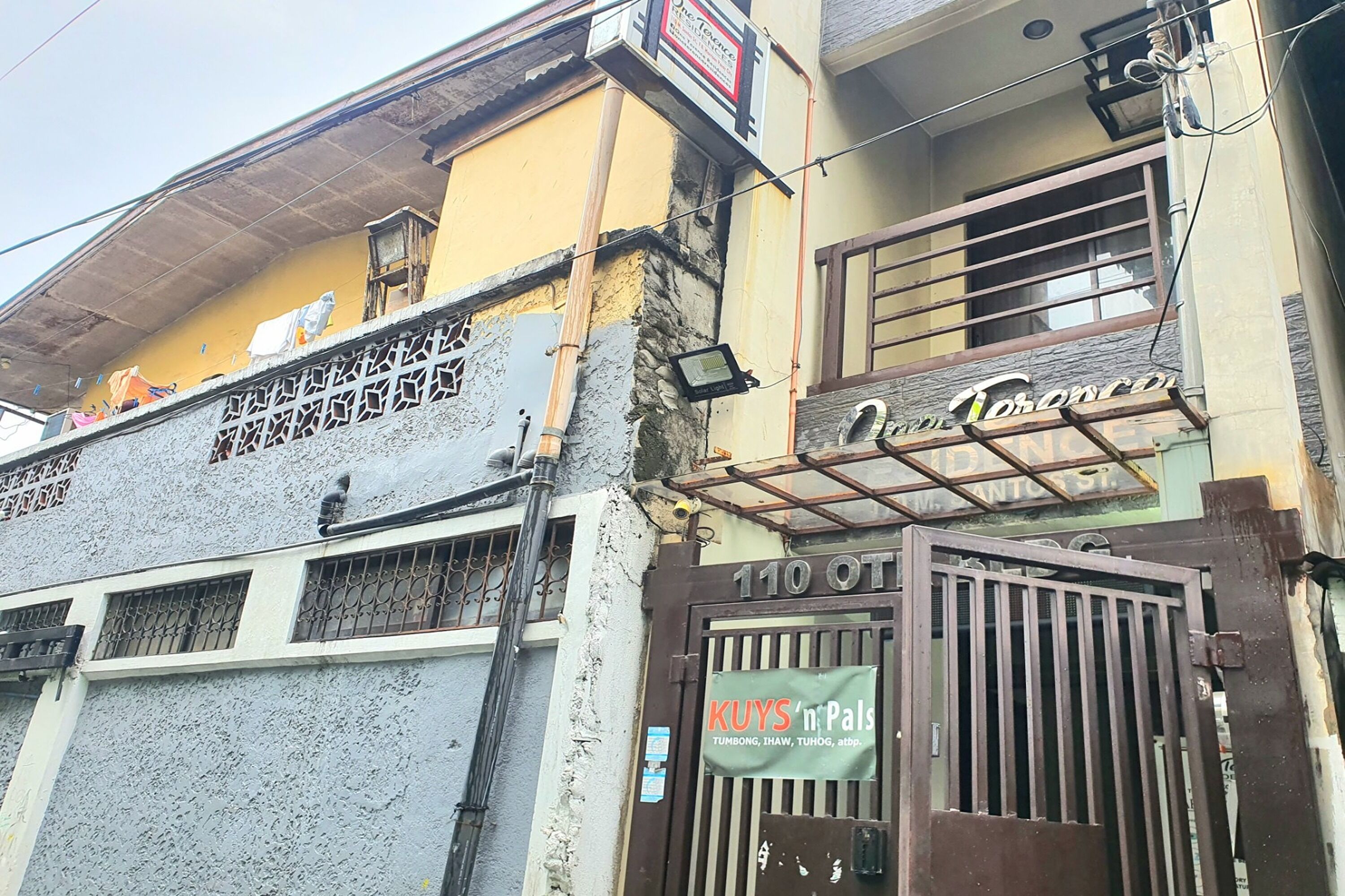 A building with a sign for 'Tosancpi' and a gate labeled '110 OT'.